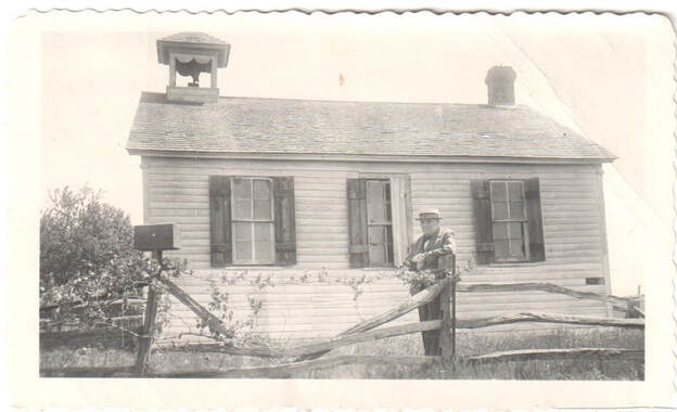A.M. Henderson in front of Sheldall Schoolhouse with ballot box used in 1860 election.